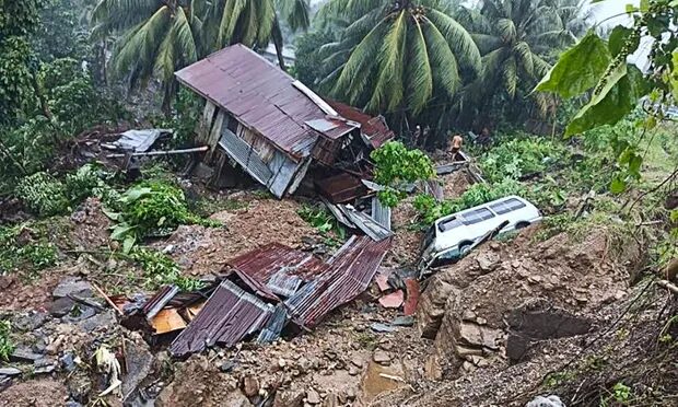 A resident beside a damaged house and vehicle after a landslide in Parang town in Maguindanao province, southern Philippines.