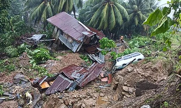 Click to enlarge A resident beside a damaged house and vehicle after a landslide in Parang town in Maguindanao province, southern Philippines.