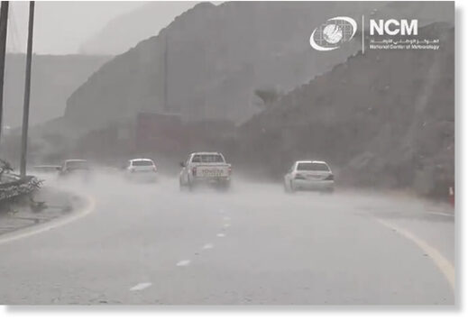 Vehicles pass by a road during heavy rain.