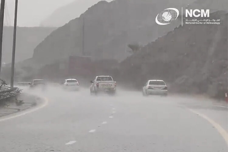 Vehicles pass by a road during heavy rain.
