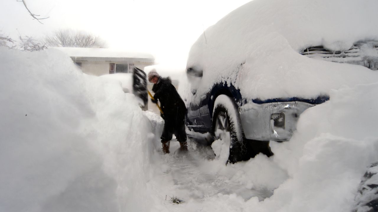 Heather Ahmed uses a shovel to dig a path next to a vehicle after an intense lake-effect snowstorm impacted the area Friday in Hamburg, New York.