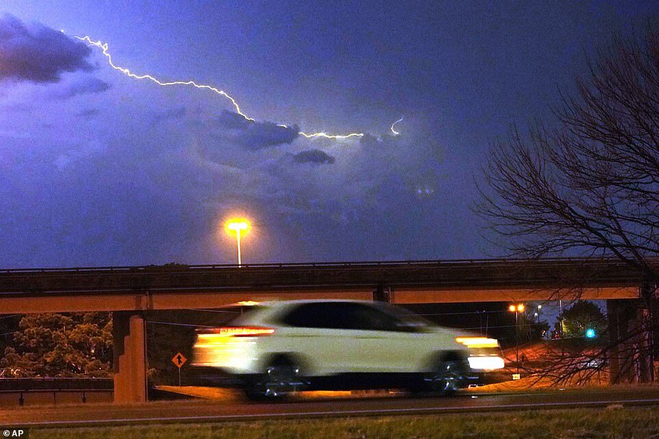 Click to enlarge A vehicle races along a Jackson, Miss., street as lightning streaks across the sky, Tuesday evening, Nov. 29, 2022