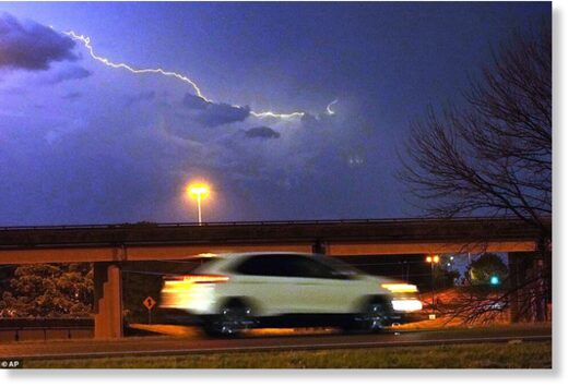 A vehicle races along a Jackson, Miss., street as lightning streaks across the sky, Tuesday evening, Nov. 29, 2022