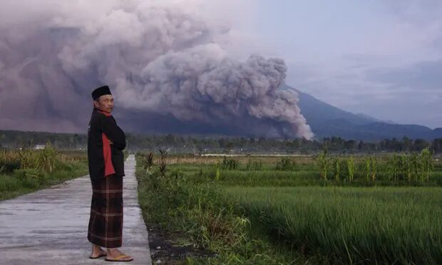A man looks on as Mount Semeru releases volcanic materials during an eruption on Sunday.