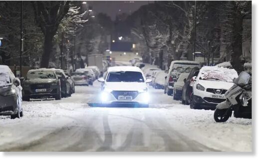 A car drives along a snow-covered road in the early morning at Willesden Green, north-west London.