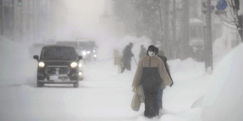 People walk through wind and snow on Monday morning in Shibetsu, Hokkaido.