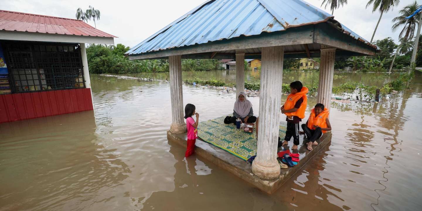 A family sits in a pergola surrounded by floodwaters in Pasir Mas in Malaysia’s northern Kelantan state on December 21, 2022.
