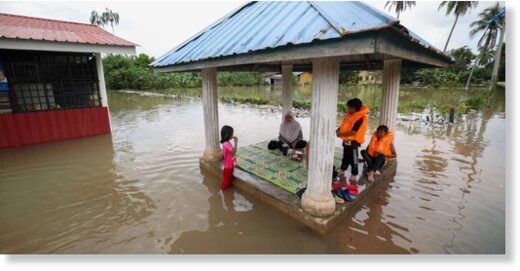Click to enlarge A family sits in a pergola surrounded by floodwaters in Pasir Mas in Malaysia’s northern Kelantan state on December 21, 2022.