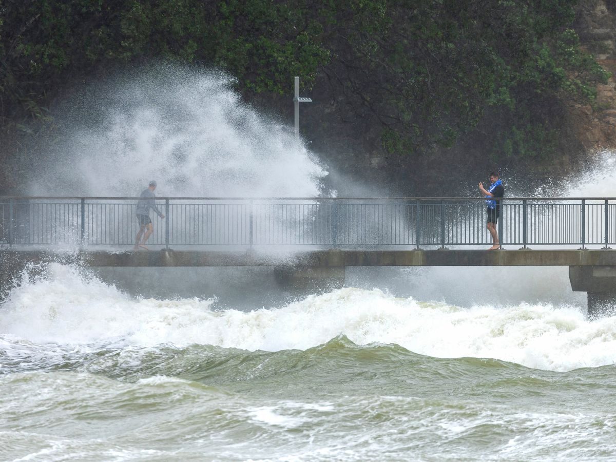 People watch as waves crash against the cliffs in Auckland