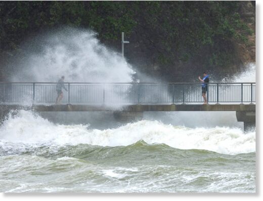 People watch as waves crash against the cliffs in Auckland