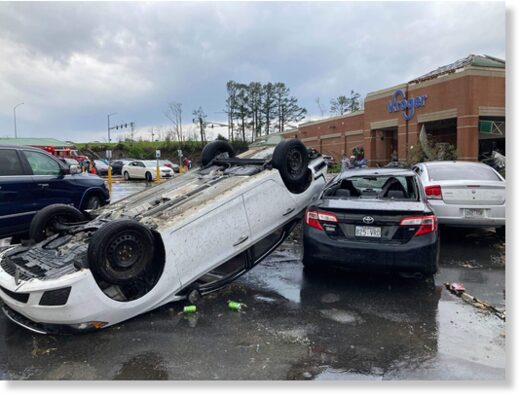 Click to enlarge A car is upturned in a parking lot after the severe