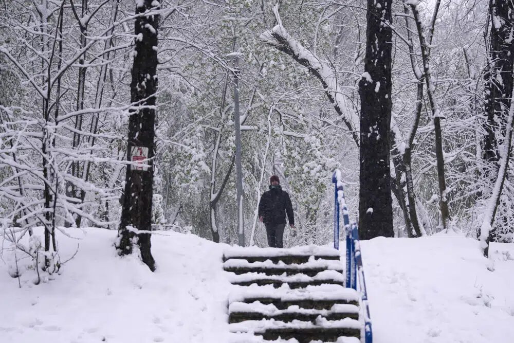 A man walks through a snow covered park