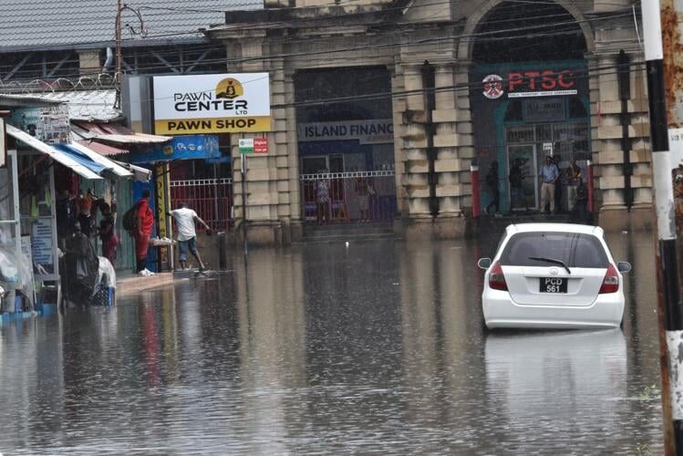 Widespread: Lower Henry Street leading onto South Quay, left, was covered in water, making it impassable to both vehicular and pedestrian traffic following yesterday’s heavy rains in downtown Port of Spain.