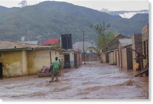 Click to enlarge A man tries to cross a flooded street in Uvira,