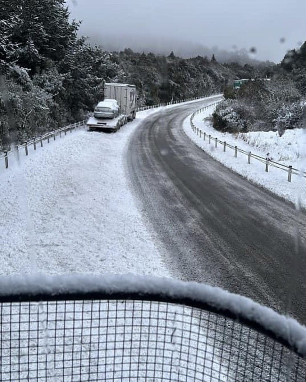 Snow falling at sea level on the Dunedin to Waitati Highway, causing traffic disruptions.|