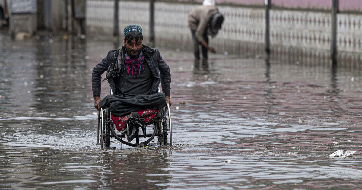 File photo: A man on a wheelchair makes his way through flood waters after heavy rains in Kabul on April 24, 2022