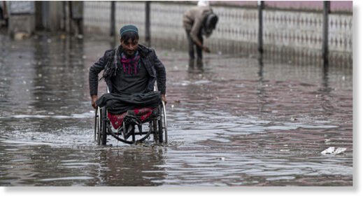 Click to enlarge File photo: A man on a wheelchair makes his way through flood waters after heavy rains in Kabul on April 24, 2022