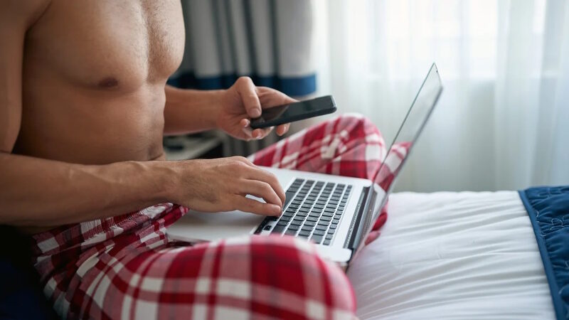man laptop pajamas shirtless stock photo