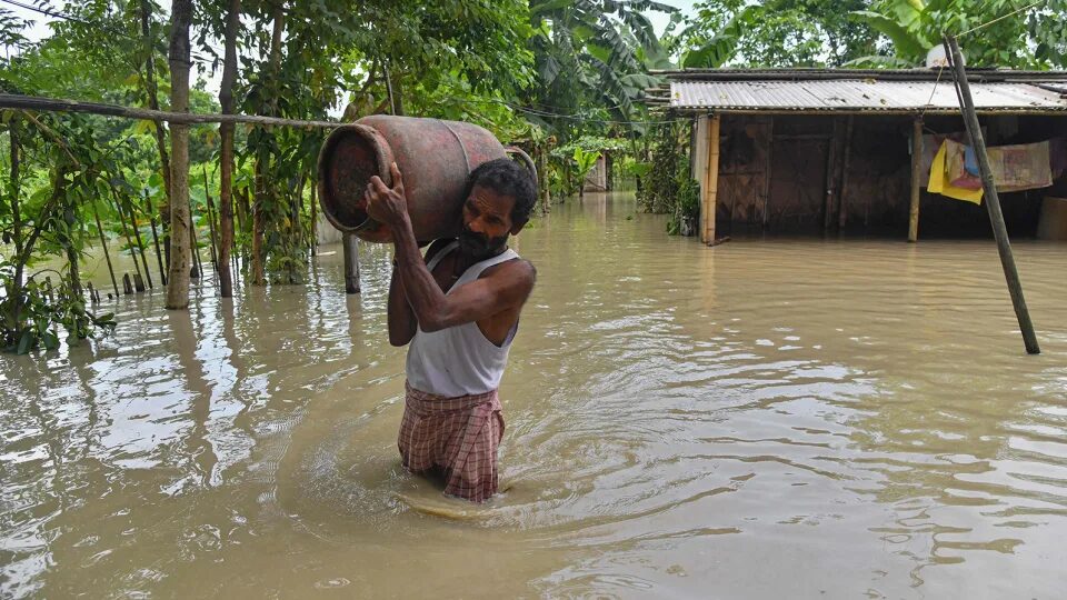 Click to enlarge A man carries belongings from his partially submerged house in the flood affected Dhamdhama village of Nalbari district, in India's Assam state on June 22, 2023.