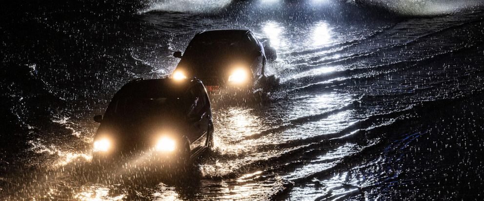 Vehicles drive through a flooded section of the A59 highway as heavy rain falls, Thursday evening, June 22, 2023, in Duisburg, Germany.