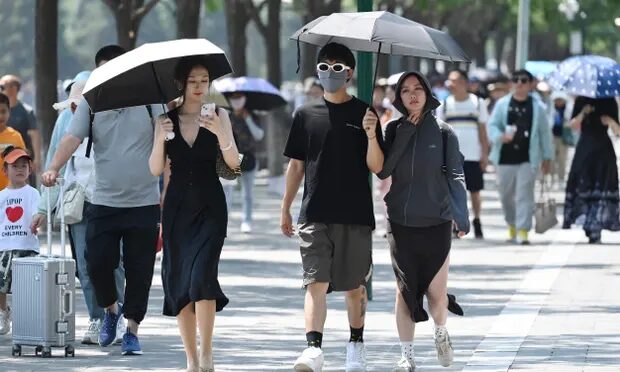 People shelter from the sun under umbrellas in Beijing on Saturday