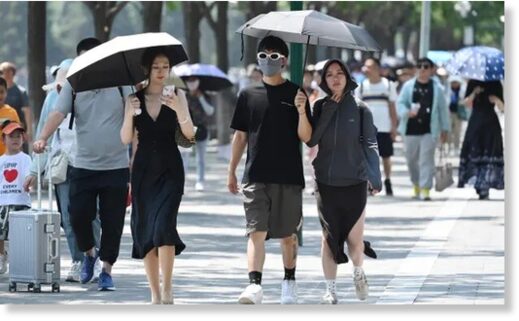 People shelter from the sun under umbrellas in Beijing on Saturday