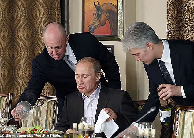 Click to enlarge Yevgeny Prigozhin (left) assists Vladimir Putin (centre) during a dinner