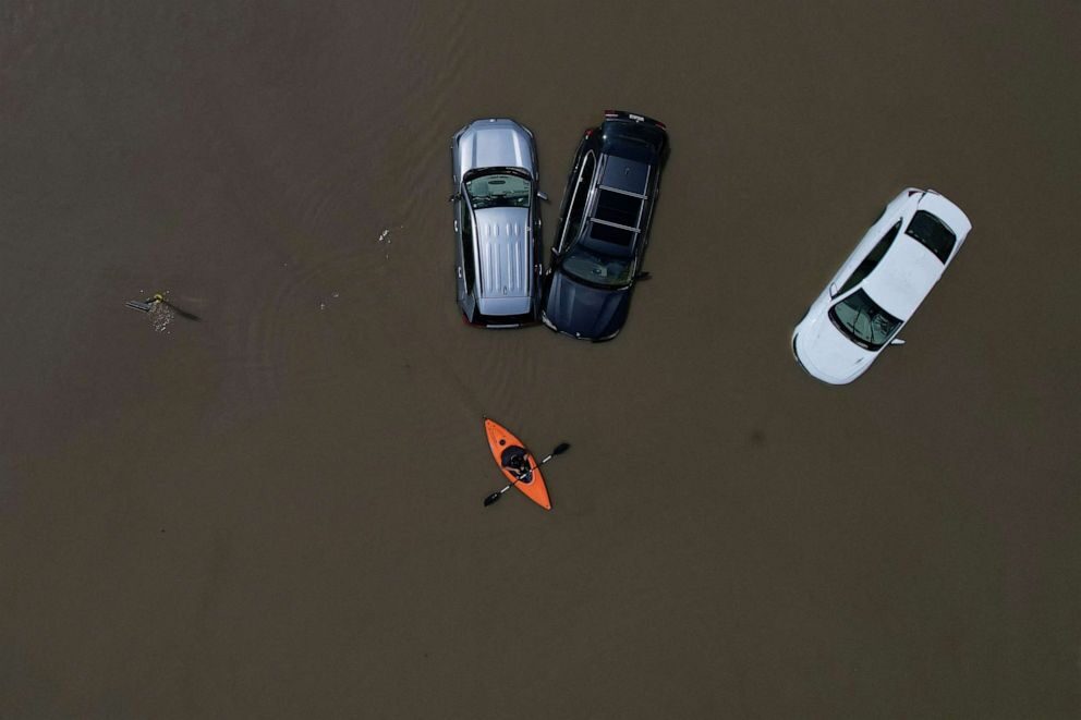 Click to enlarge A person in a canoe passes parked cars partially submerged by floodwaters from recent rainstorms in Montpelier, Vermont, on July 11, 2023.
