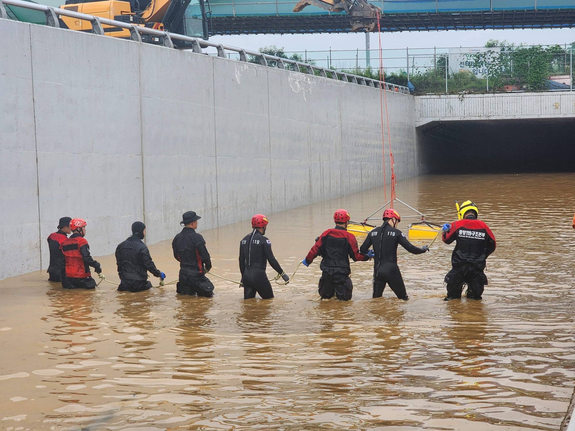 South Korean rescue workers search for missing people on a submerged road leading to an underground tunnel in Cheongju.