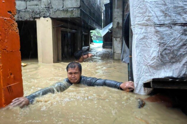A man negotiates neck-deep floodwaters