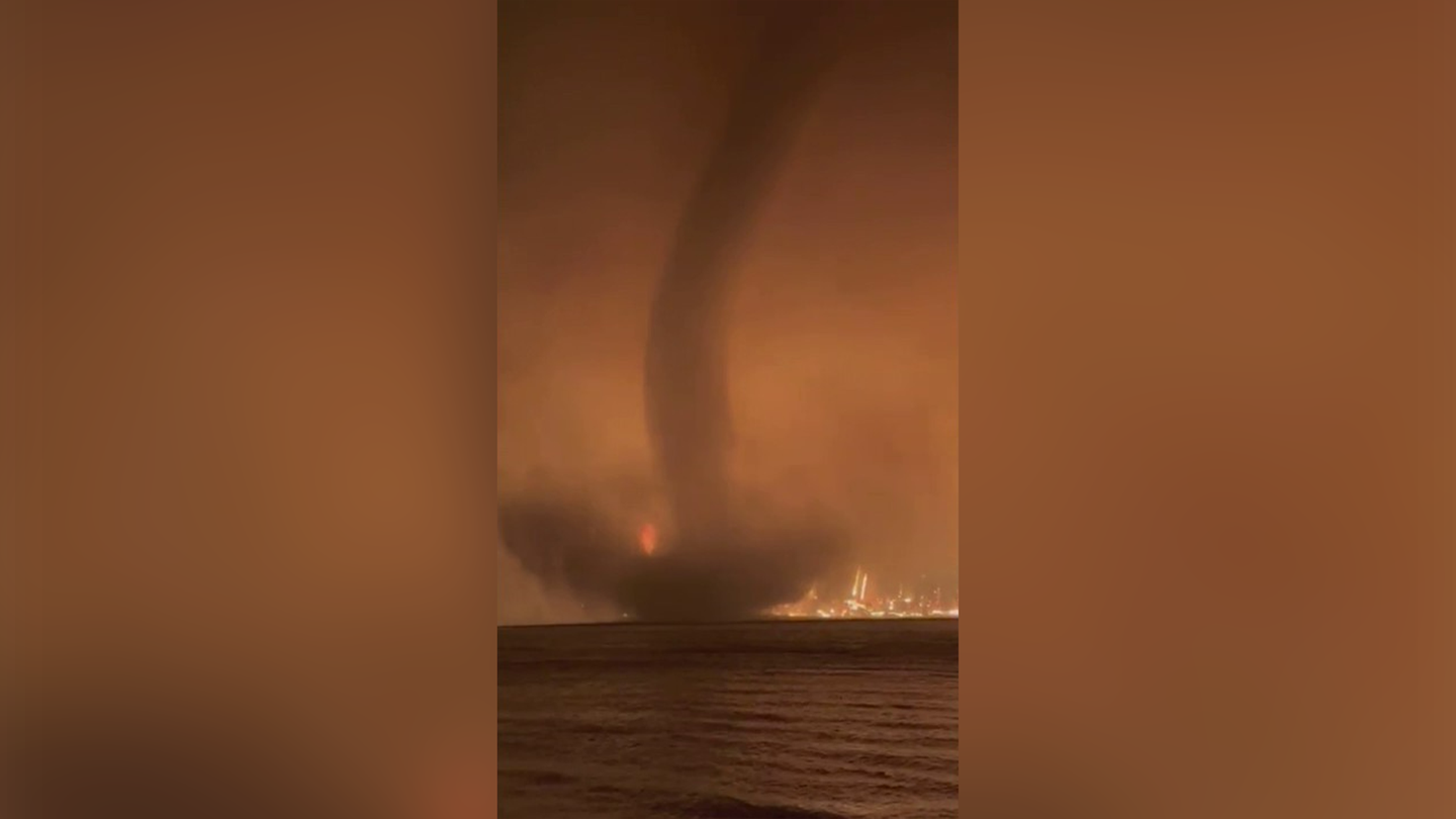 A waterspout is seen spinning in front of a massive wildfire in Canada.