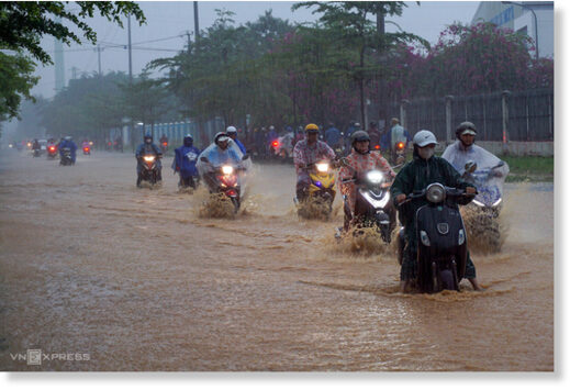 Motorcyclists ride on a flooded road in Da Nang under heavy rain at 7 a.m. on September 25, 2023.