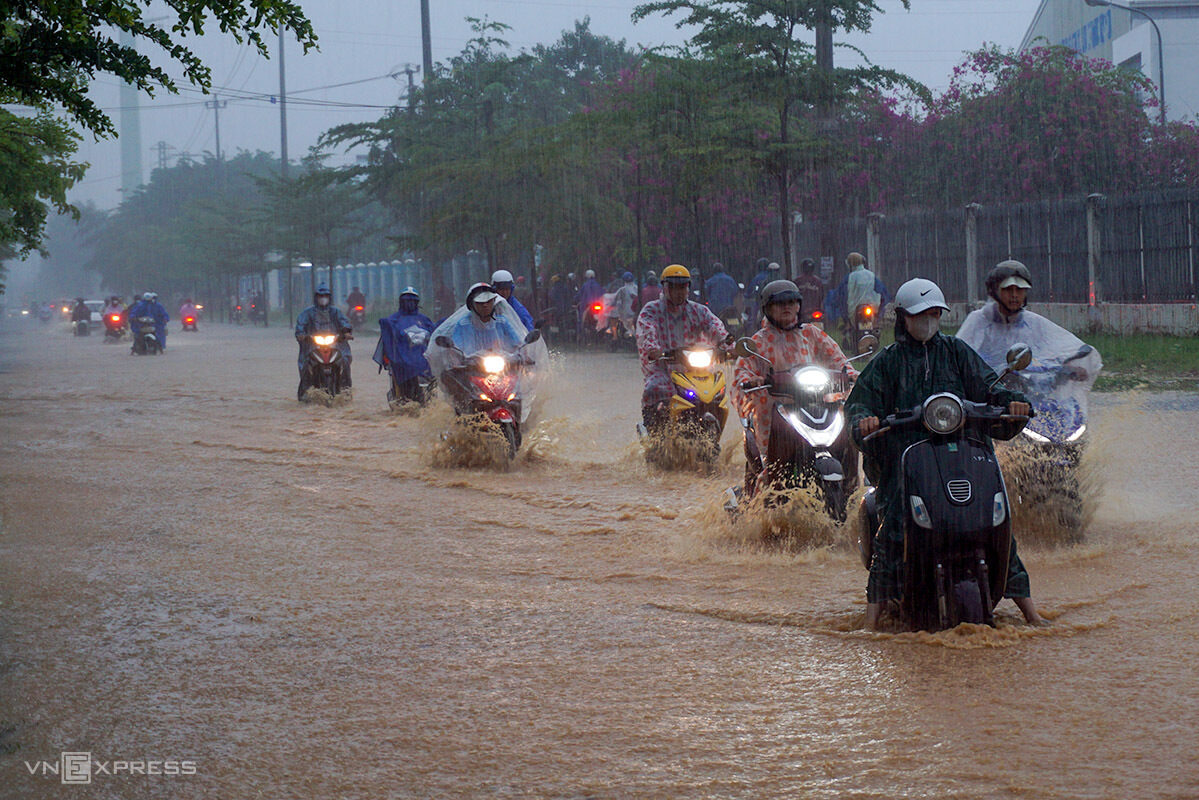 Motorcyclists ride on a flooded road in Da Nang under heavy rain at 7 a.m. on September 25, 2023.