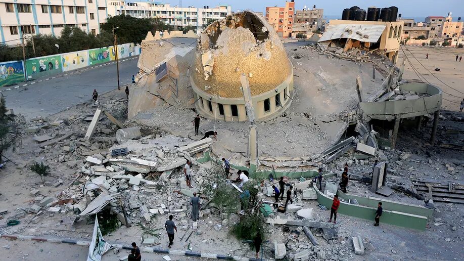 People stand outside a mosque destroyed in an Israeli air strike in Khan Younis, Gaza Strip