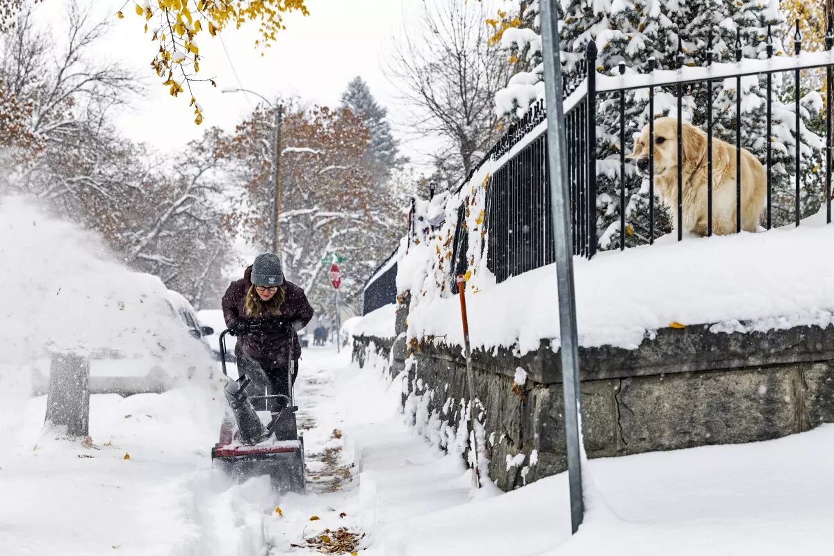 A person clears a snow-covered sidewalk in Helena, Mont., on Wednesday.