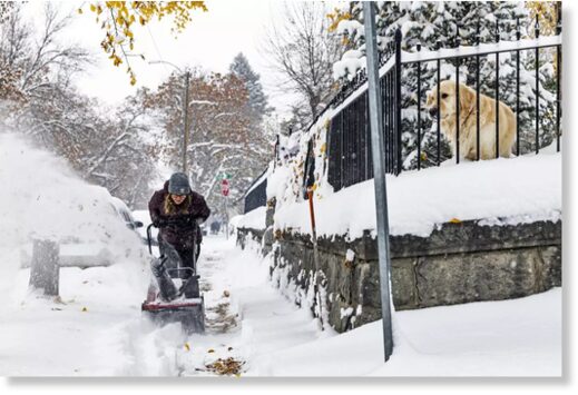 A person clears a snow-covered sidewalk in Helena, Mont., on Wednesday.