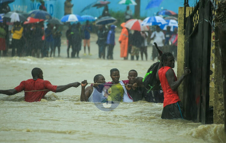 Click to enlarge A woman is assisted to safer ground after heavy