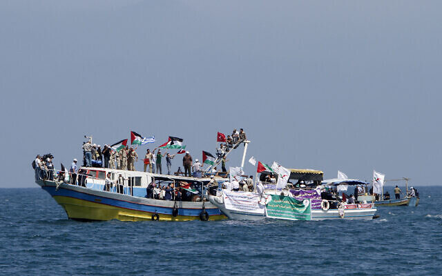 Palestinians waving national flags wait aboard small boats