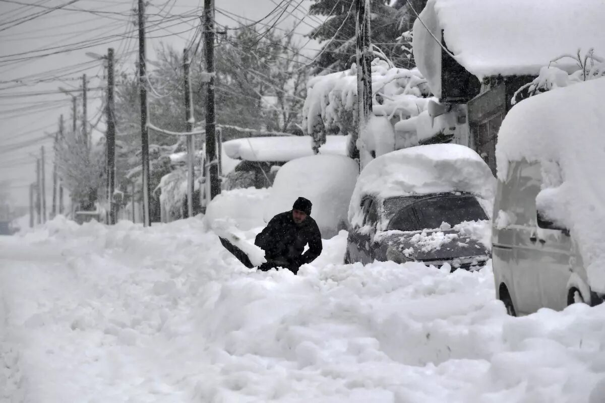 A man shovels snow, as he tries to clear his car in town of Isperih, Northeast Bulgaria, Sunday, Nov. 26, 2023.