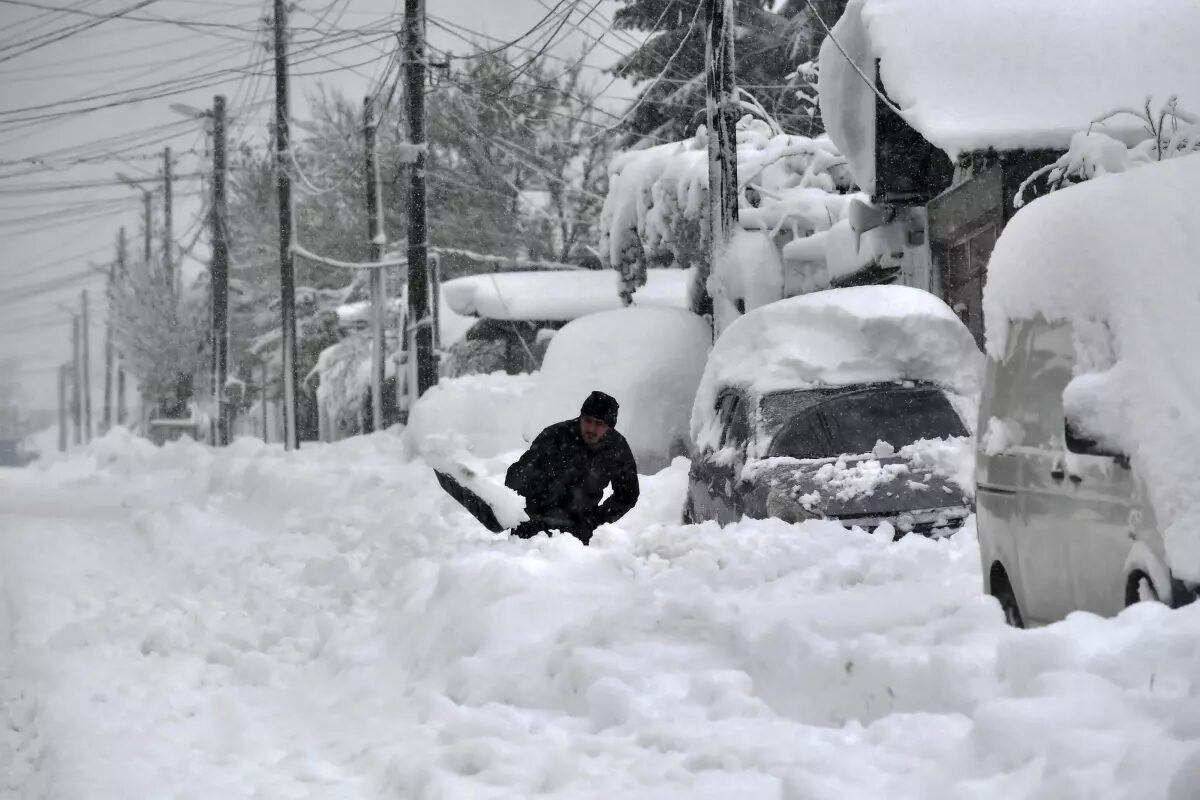 Click to enlarge A man shovels snow, as he tries to clear his car in town of Isperih, Northeast Bulgaria, Sunday, Nov. 26, 2023.