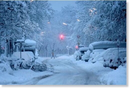 A man crosses a road early in the morning after heavy snowfall in Munich