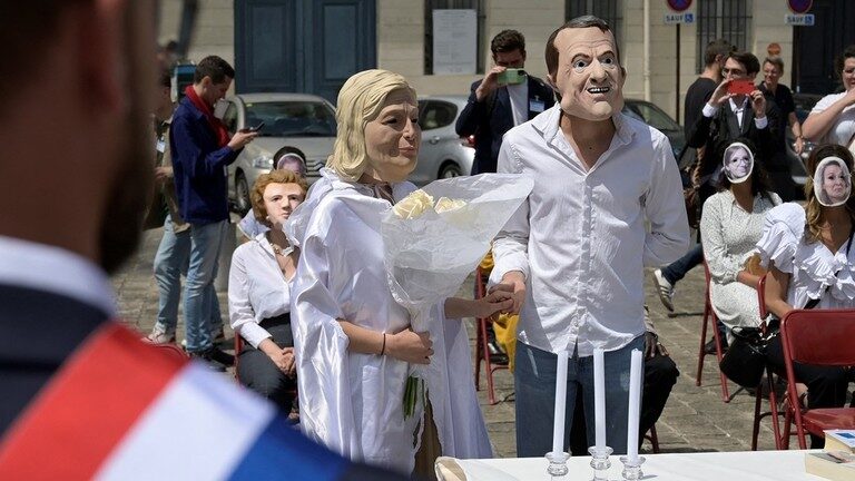 French activists posing as President Emmanuel Macron and Marine Le Pen perform a fake wedding to denounce government policy, in 2022.