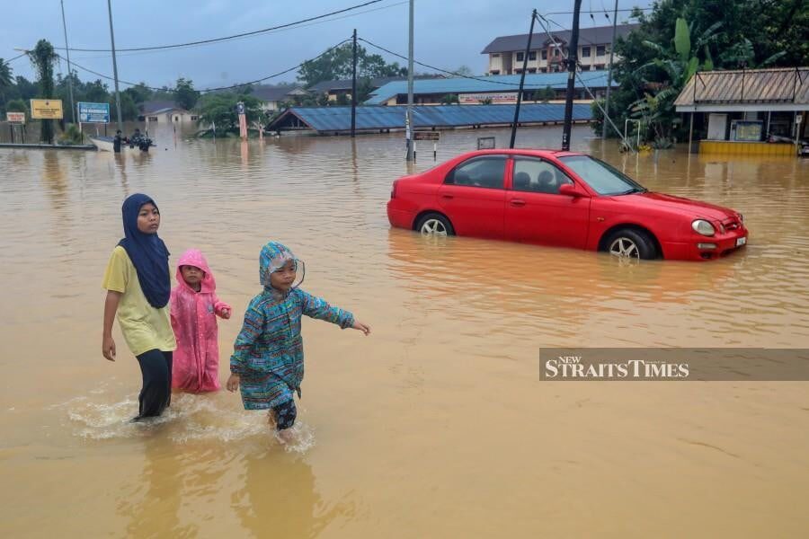 Children wade through floodwaters in Bandar Kuala Berang, Kuala Terengganu, followiing heavy rain.