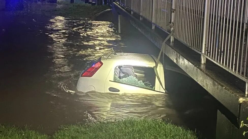 West Midlands Police praised a bystander who waded into flood water and rescued a three-year-old child and the driver, before securing the vehicle to a bridge
