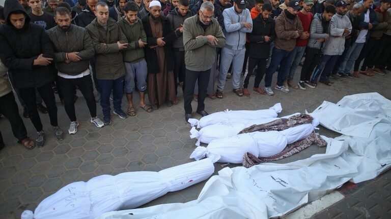 Palestinians pray by shrouded bodies of people killed following Israeli bombardment in the Gaza Strip.