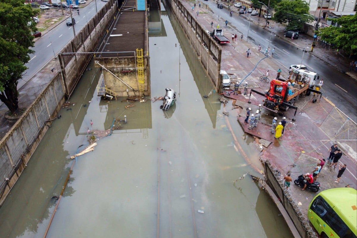 People look at a car that was swept into the flooded railways of the Acari metro station after heavy rains caused destruction in the suburbs of Rio de Janeiro, Brazil on Sunday.