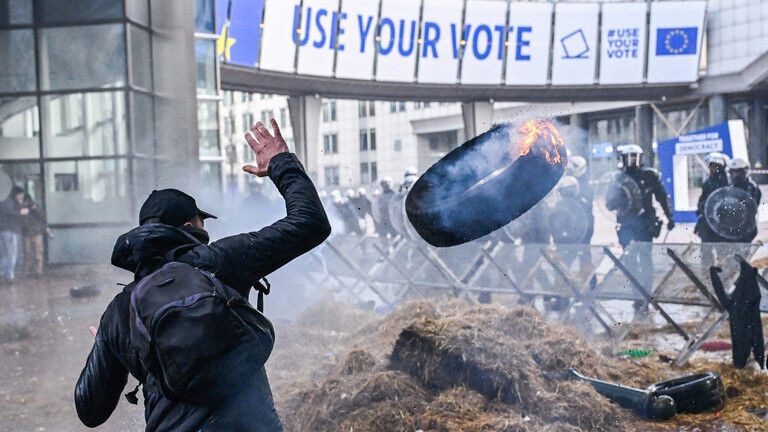Protester throws a burning tyre in front of police forces during the farmer protest action in the European district in Brussels, Belgium