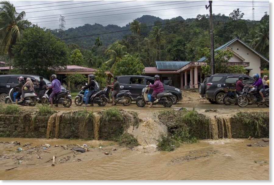 Motorists drive through a muddy road following flash flooding in Pesisir Selatan Regency after days of heavy rain across the province.