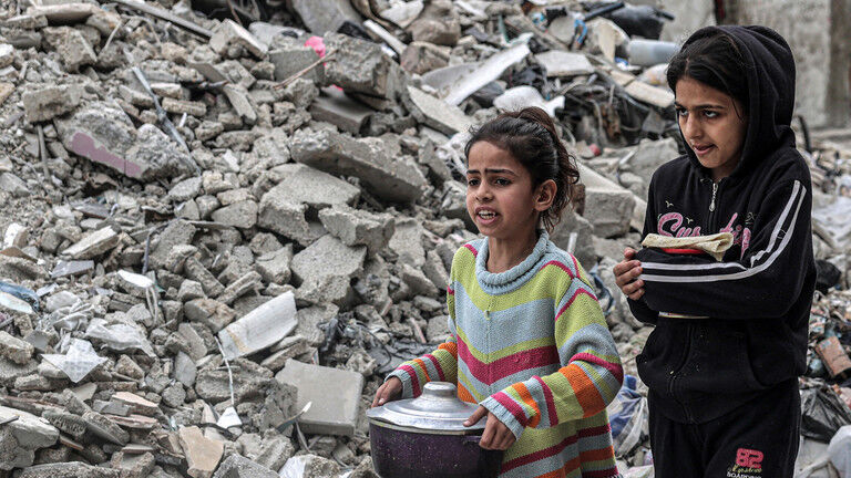 Children walk past the rubble of a collapsed building in Gaza, March 16, 2024.