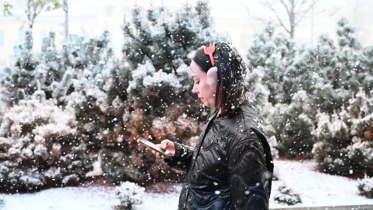 Click to enlarge A woman walks along a street during rare spring snowfall in Moscow, Russia.